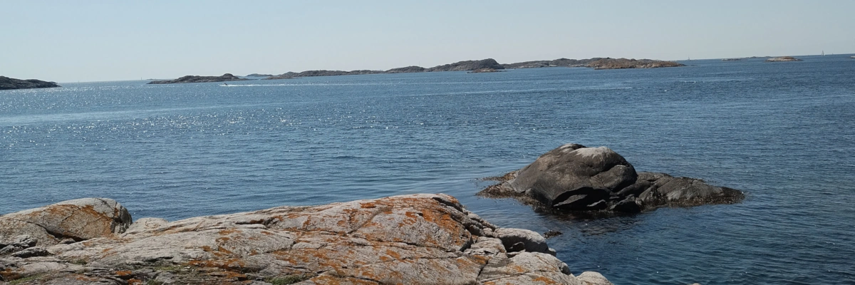 Standing on a big rock overlooking the sea, seeing more rocky formations in the distance.